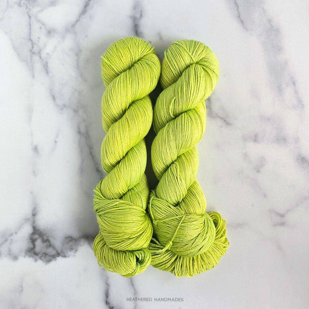 Two skeins of bright green yarn on a marble surface