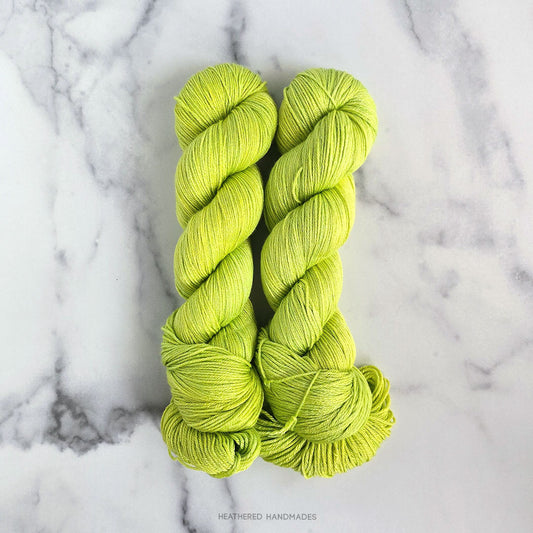 Two skeins of bright green yarn on a marble surface