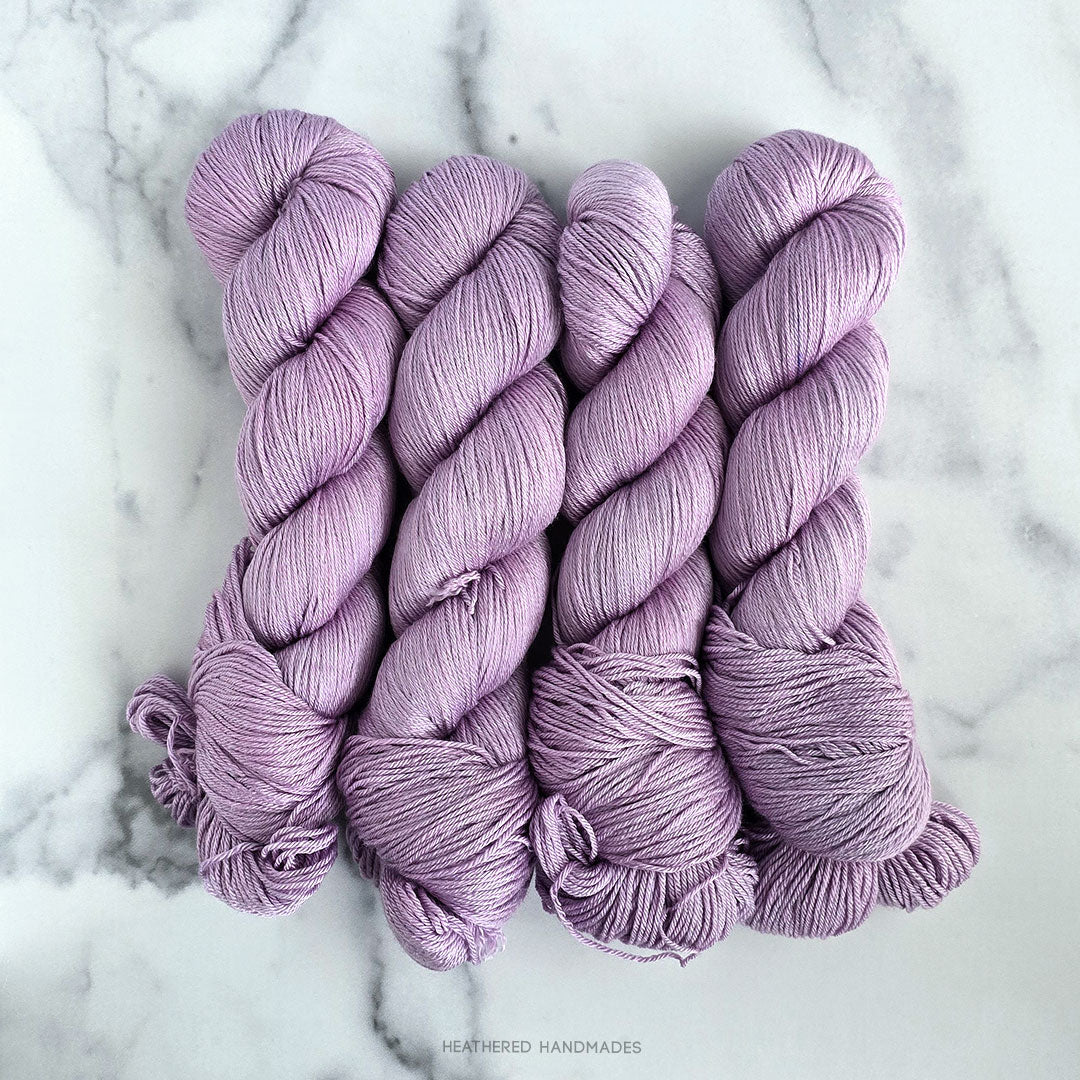 Three skeins of purple yarn on a marble surface