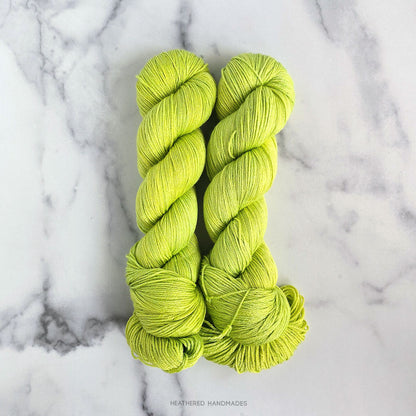 Two skeins of bright green yarn on a marble surface