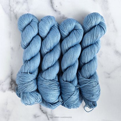 Four skeins of blue yarn on a marble surface