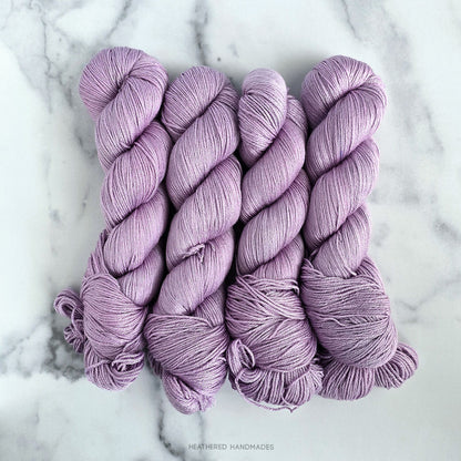 Three skeins of purple yarn on a marble surface